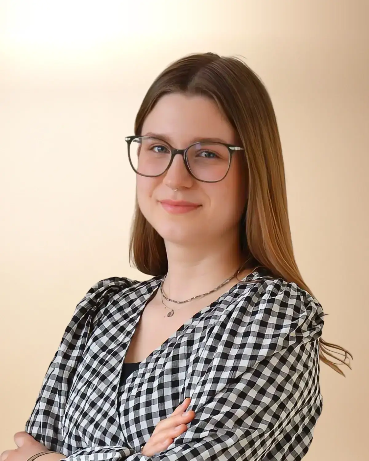 Karolina Kerner, logopeda, w koszuli w kratę i okularach, z długimi włosami